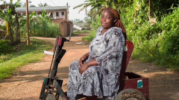 A woman sits on a basic mobility scooter in Cameroon