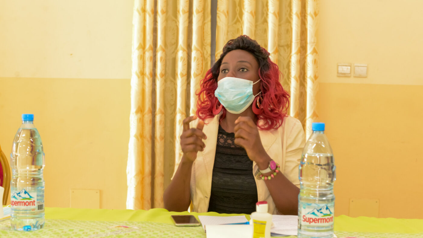 Pascaline sits at a table during a training session with a face mask on.